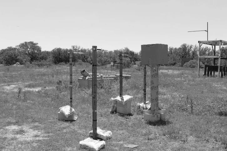 Black-and-white photograph of the test field with pressure transducer stands and a box mounted on a tube.