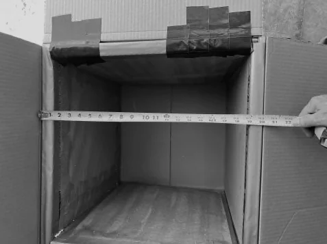 Inside of a corrugated box lined with panels along the walls, with a tape measure across it.